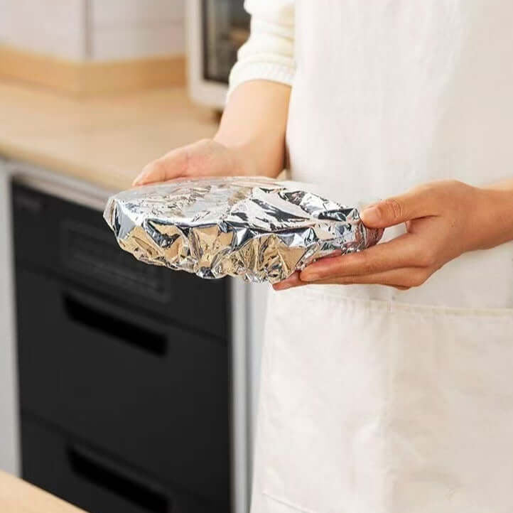 Person holding Aluminum Foil Food Covers to keep food warm and maintain serving temperatures in the kitchen.