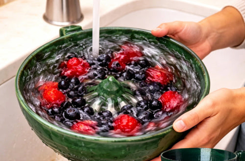 Berry Vortex Washing Bowl filled with fresh berries being rinsed in a kitchen sink.