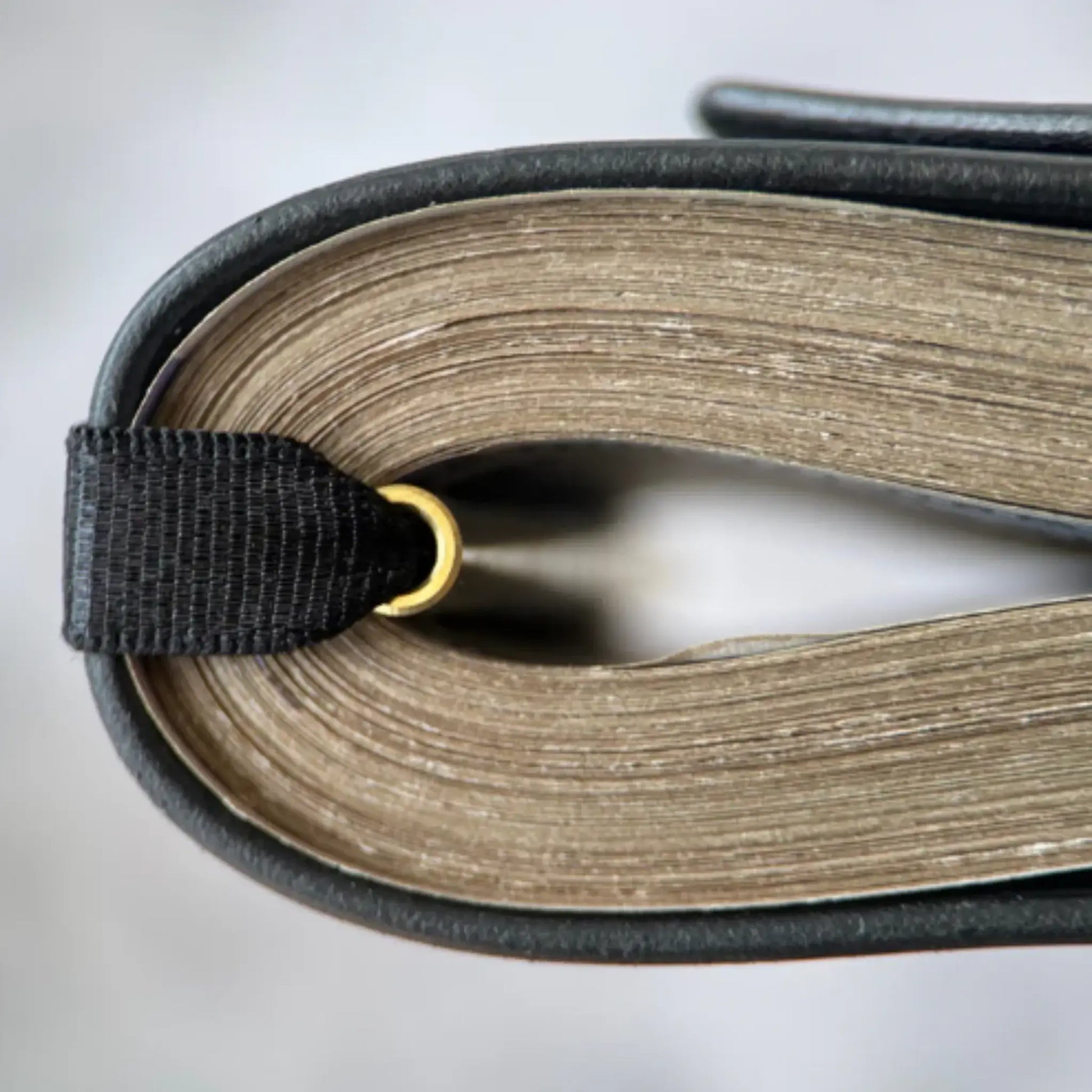 Close-up of the edge of a book with a black ribbon bookmark and a gold ring. Genuine Leather Cash Wrap Wallet