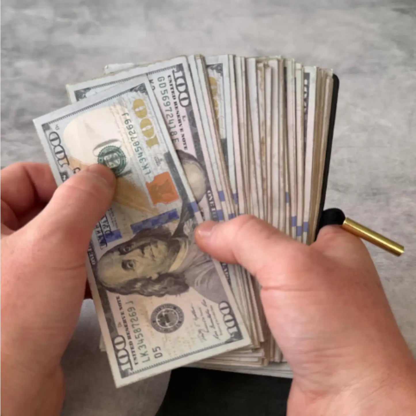 Person holding a stack of cash in a genuine leather cash wrap wallet showing its spacious design.