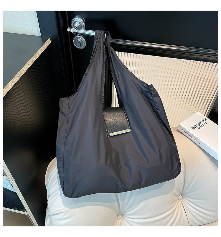 Foldable Lightweight Shoulder Bag in black color displayed on a stylish surface with a key ring capsule.