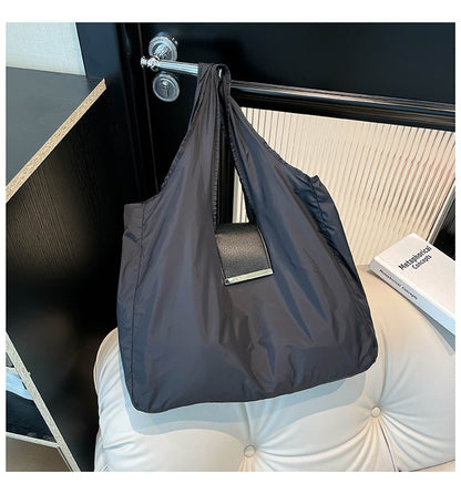 Foldable Lightweight Shoulder Bag in black color displayed on a stylish surface with a key ring capsule.