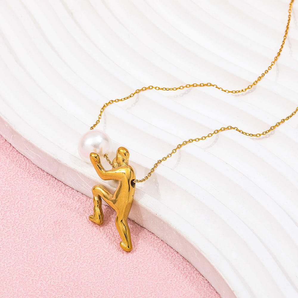 Ambition pearl necklace featuring a gold figure holding a pearl on a delicate chain against a textured background.