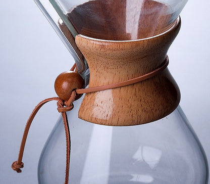 Close-up of Chemex Coffee Maker with sleek wooden collar and leather tie, showcasing premium glass design.