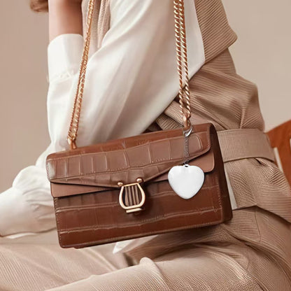 Heart Shaped Bag Light – The LUMI-HEART Glowing Handbag Charm on a brown handbag.