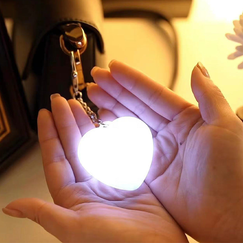 Heart Shaped Bag Light – The LUMI-HEART Glowing Handbag Charm illuminating hands with soft light.