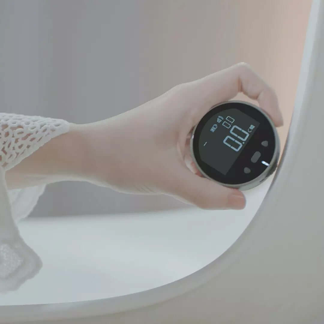 A hand in a white, lacy sleeve holds the PrecisionCore HD High Precision Electronic Measuring Ruler Tool, showing a 0.0 reading on its digital display near the edge of a white bathtub.