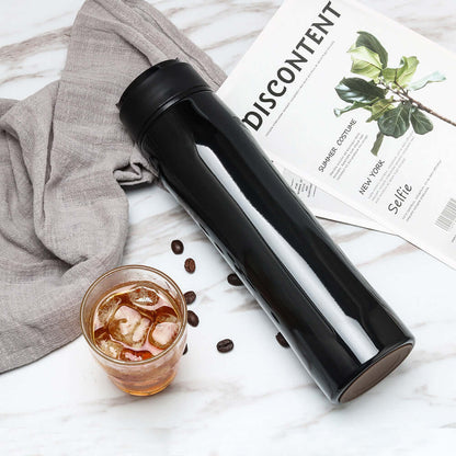 Portable Espresso Maker next to a glass of iced coffee on a marble surface.