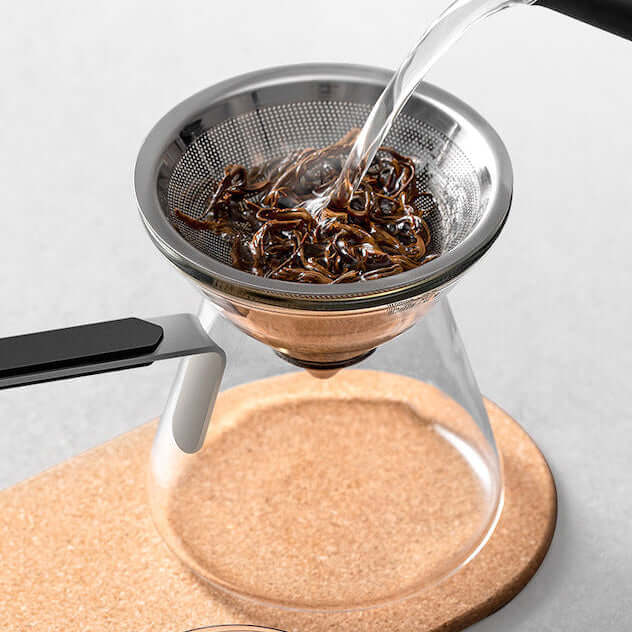 Water flowing through the strainer of a Magnetic Tea Pot, demonstrating the brewing process with loose tea leaves.