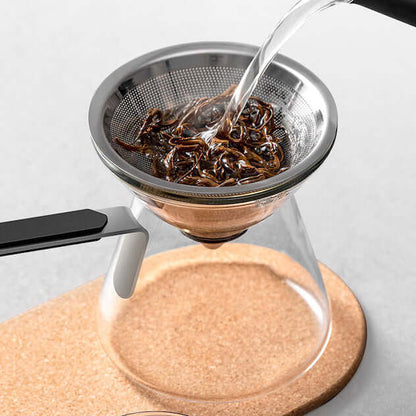 Water flowing through the strainer of a Magnetic Tea Pot, demonstrating the brewing process with loose tea leaves.
