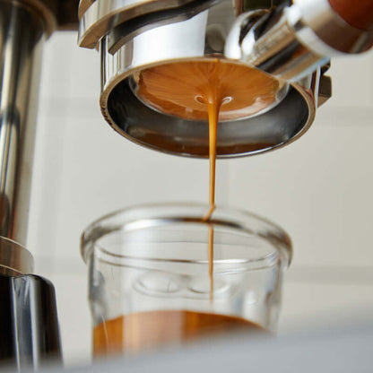 Close-up of coffee extraction from a Manual Espresso Machine into a glass cup.