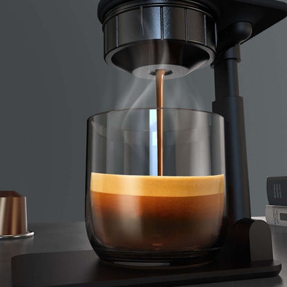 Brewed espresso shot from a Portable Electric Espresso Maker into a clear glass cup.