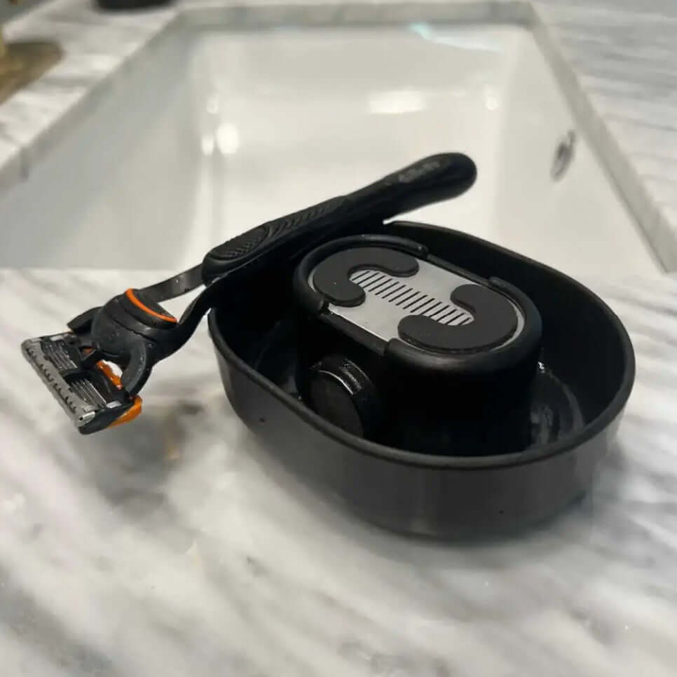 Shaver Cleaner displayed with a razor and Eco-Flush Manual Pressure Washer on a marble countertop.